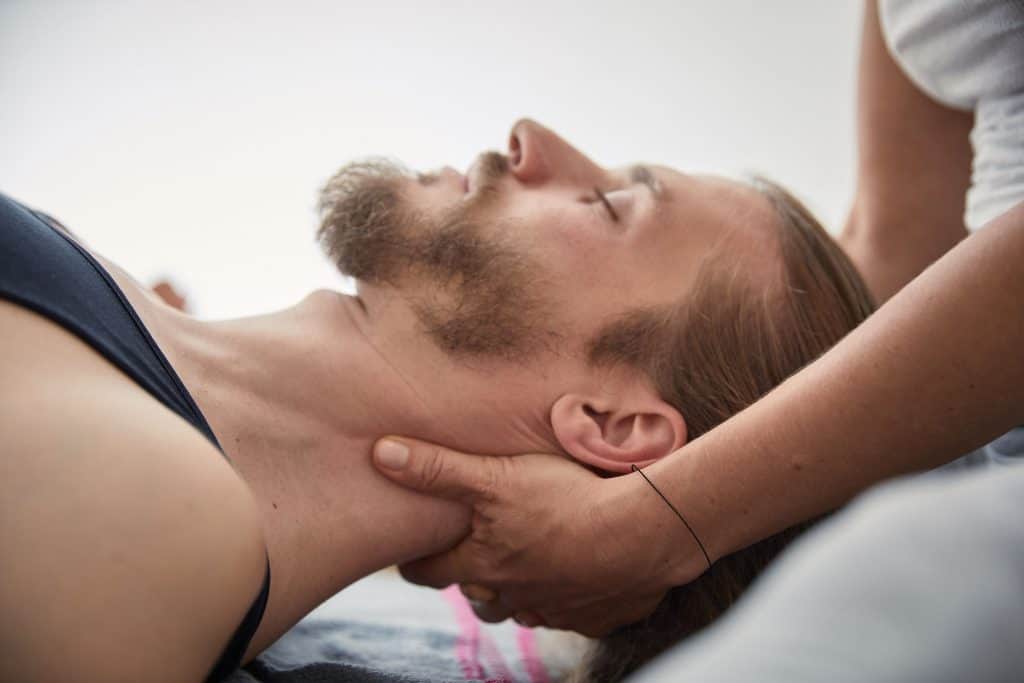 Liegender Mann bekommt Craniosacral Therapie